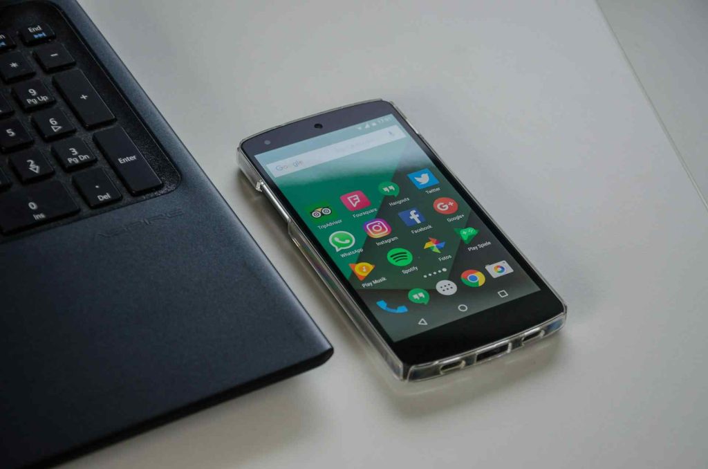 A Smartphone Placed Beside a Laptop On a White Desk