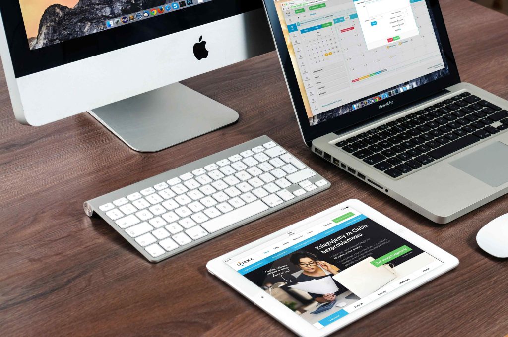 A Workspace With An iMac, MacBook Pro, and iPad Displaying Charts showcasing about modern Website development and 3d graphics.