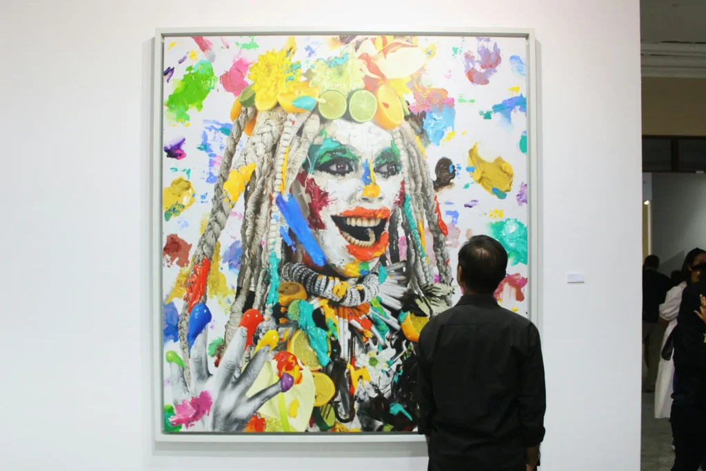 27 DiGi AI Art vs Human Art : The Ultimate Creative and Innovative Showdown 2 An art exhibition featuring a colorful, abstract mural with vivid splashes of paint and intricate textures, viewed by a visitor.
