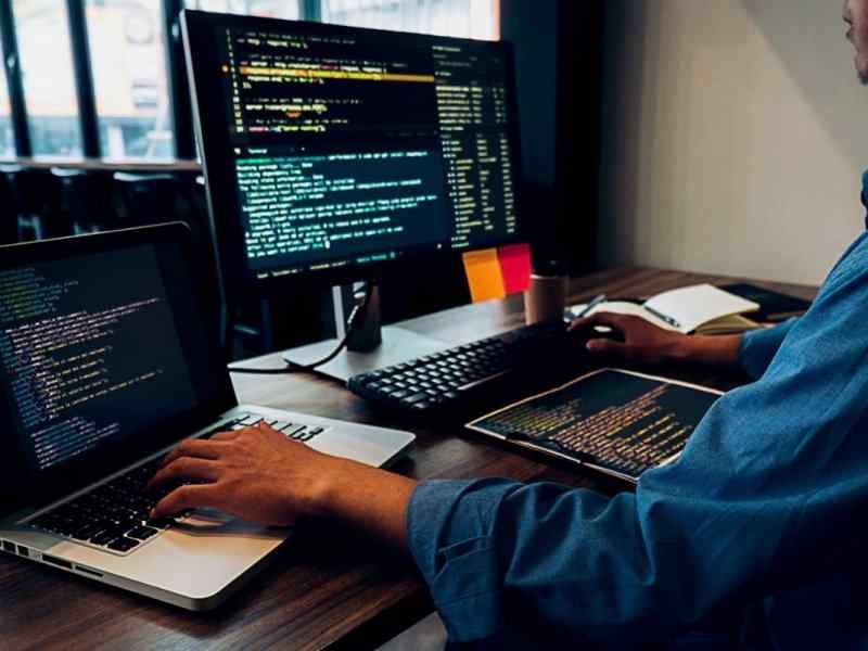 Image 12 A Person Coding For a Website On Desktop PC And On a Laptop